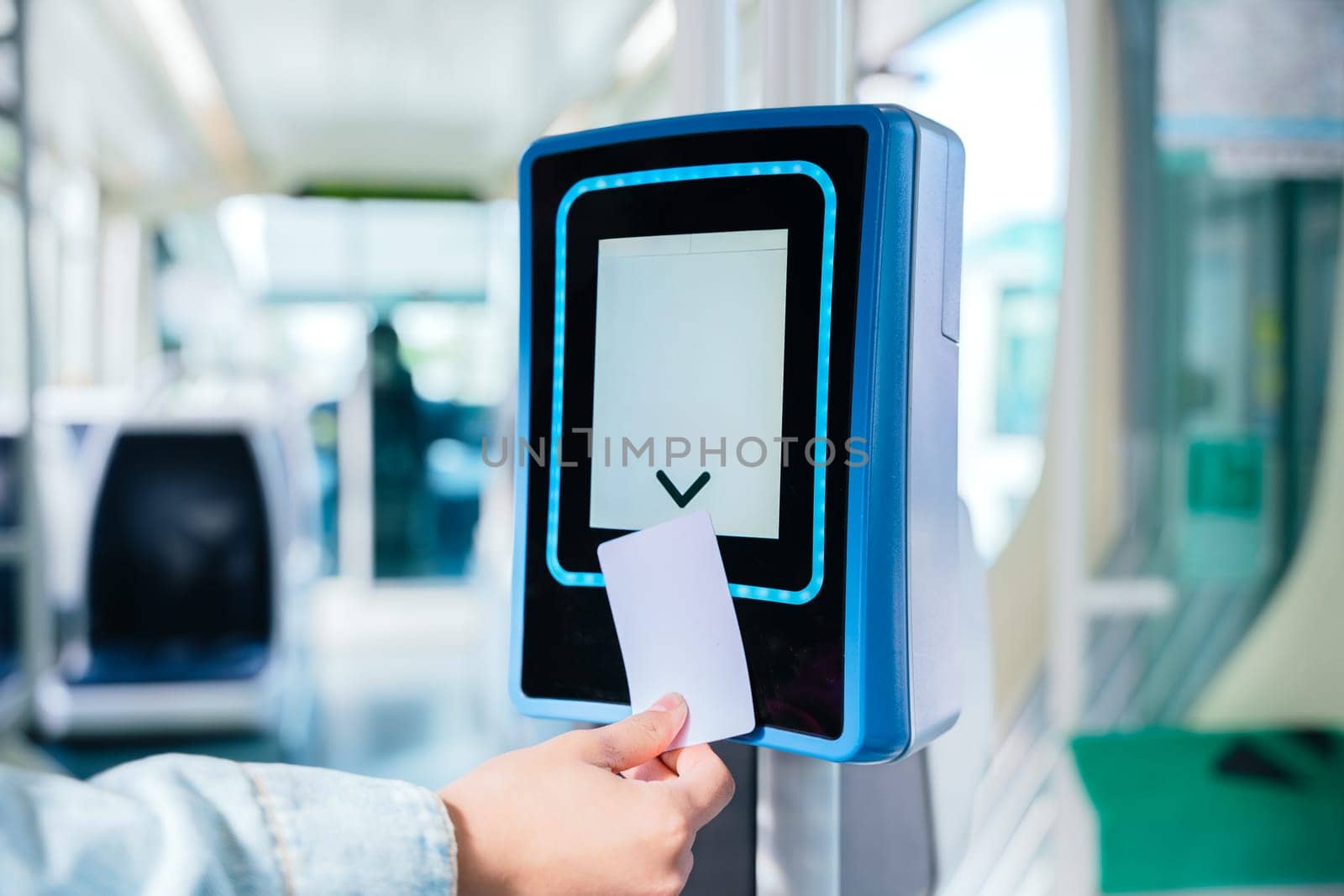 Close-up of a hand inserting a ticket into an electronic validation machine inside public transport. The modern digital system allows commuters to verify their travel access efficiently.