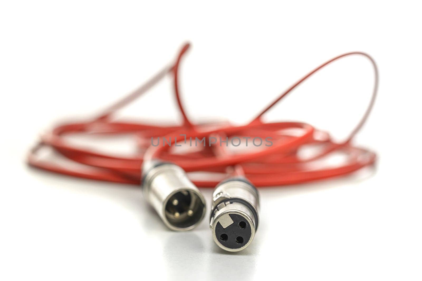 Red xlr cable connecting audio devices on white background