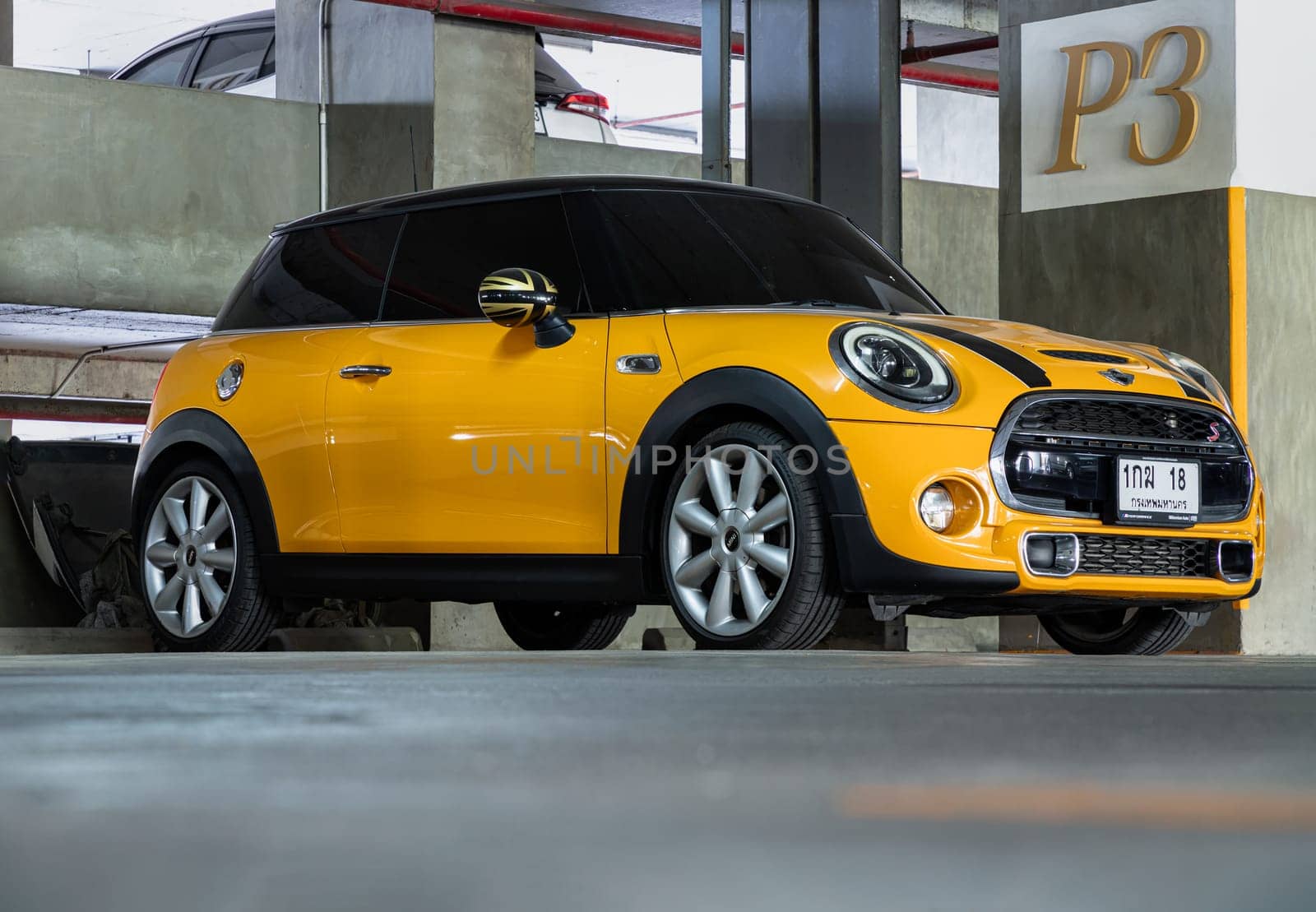 Bangkok, Thailand - 18 Jan 2025 - View of Yellow mini cooper parked parked in the parking lot of condominium building. Mini cooper is British car brands, use it as your Wallpaper, Poster and Space for text, Selective focus.