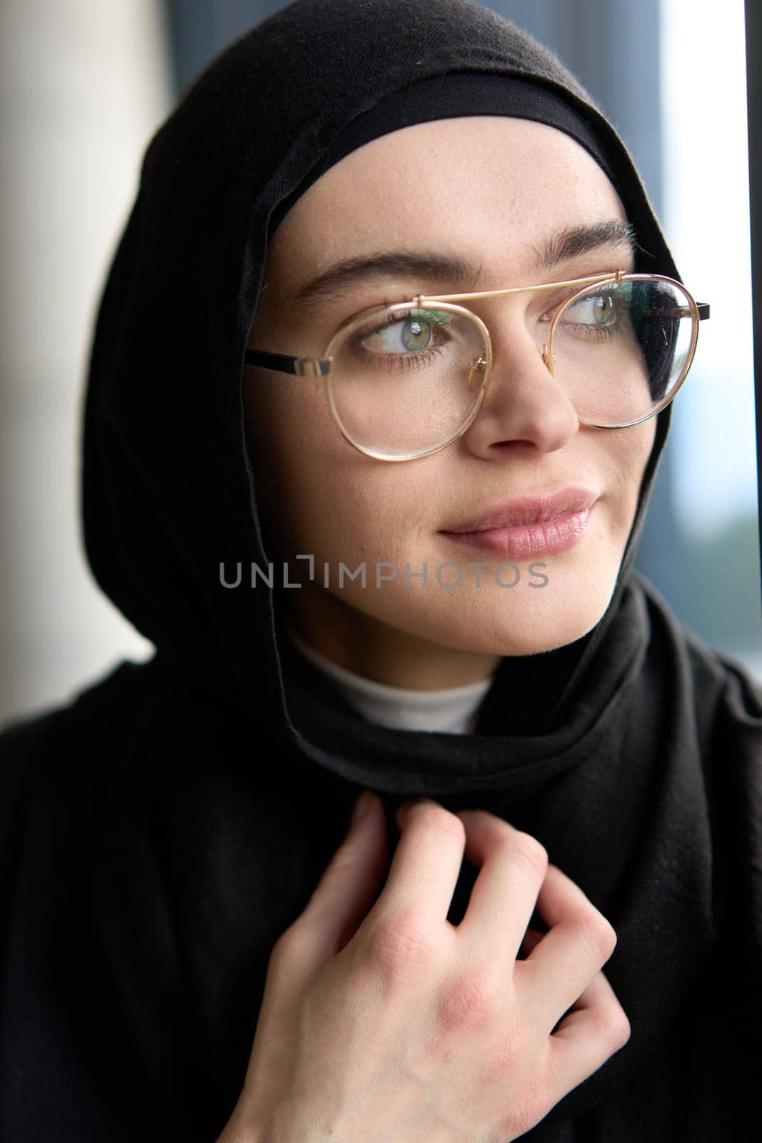 A stunning Muslim businesswoman is captured in a close-up portrait, showcasing her captivating green eyes behind stylish prescription glasses, radiating elegance and confidence.