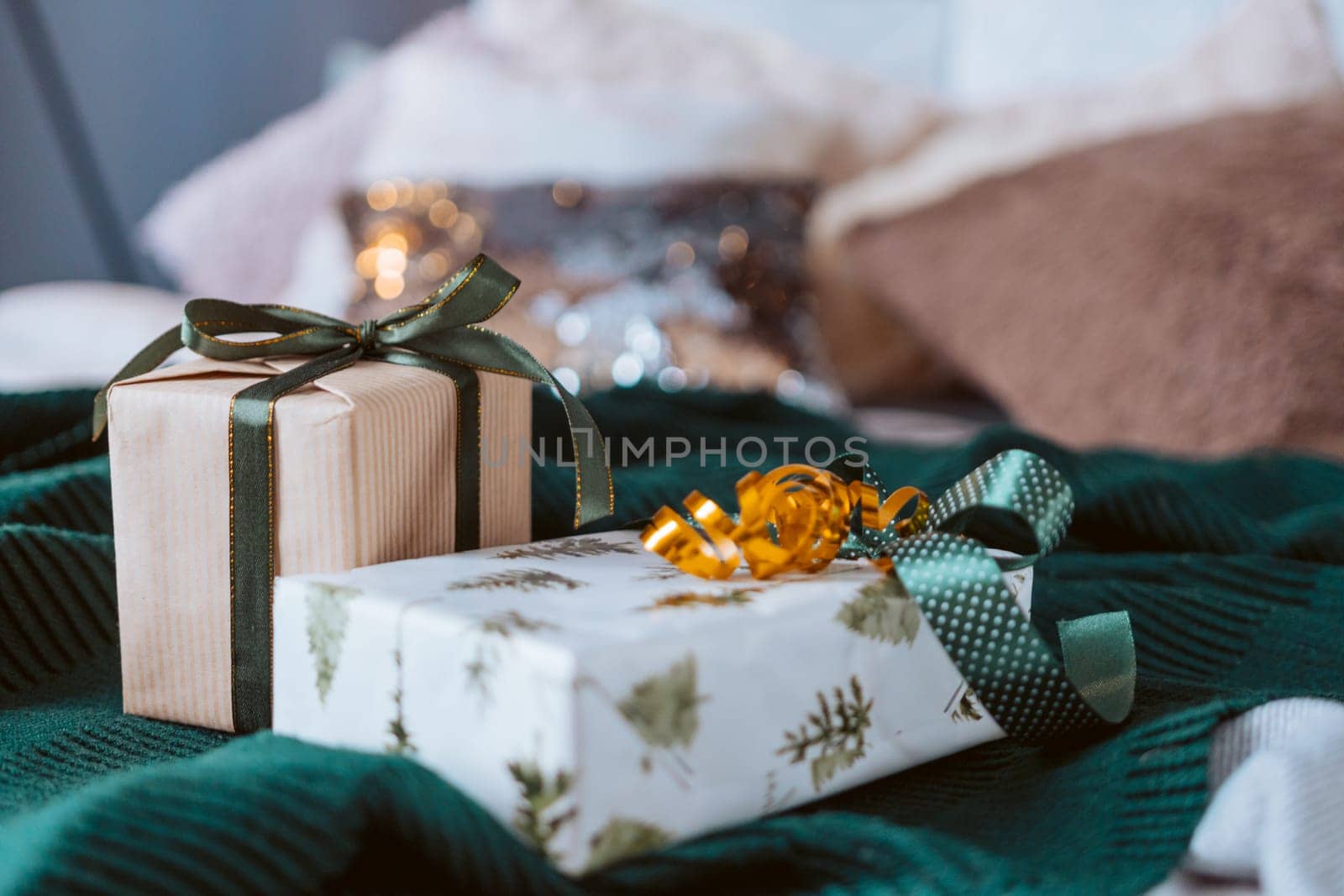 Two presents are sitting on a green blanket. One of them is wrapped in a tree patterned wrapping paper