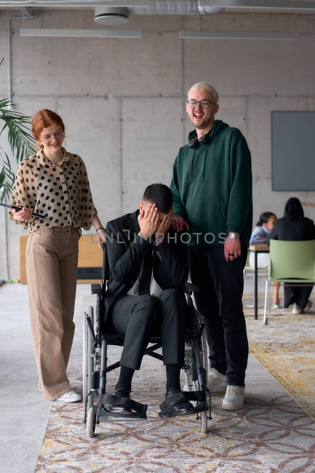 Group cheerful business colleagues, including a businessman in a wheelchair, posing together in a modern office, showcasing teamwork and inclusivity.