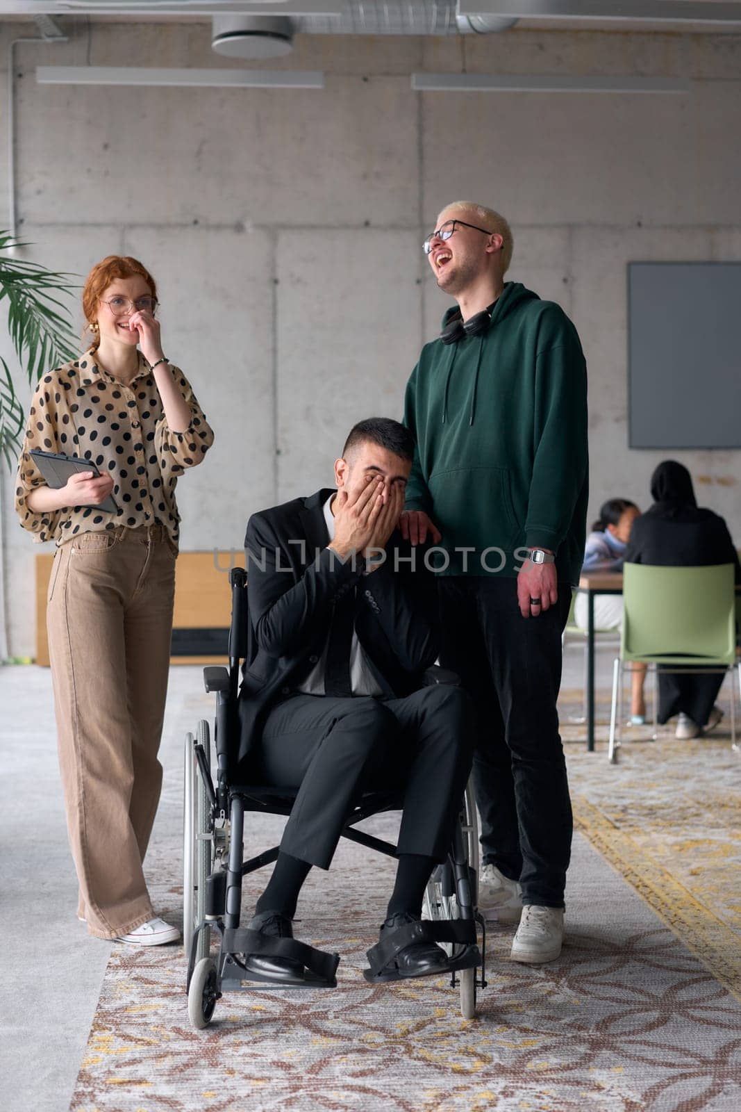 Group cheerful business colleagues, including a businessman in a wheelchair, posing together in a modern office, showcasing teamwork and inclusivity.