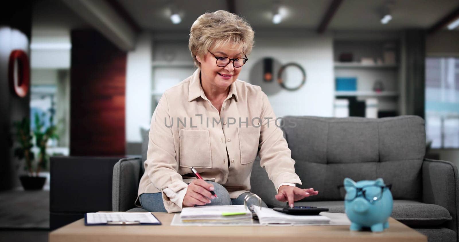 Young Woman Sitting On Sofa Calculating Bills In Her Room