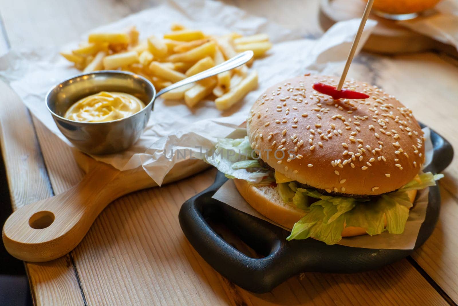 Delicious cheeseburger with french fries and mustard on wooden table.