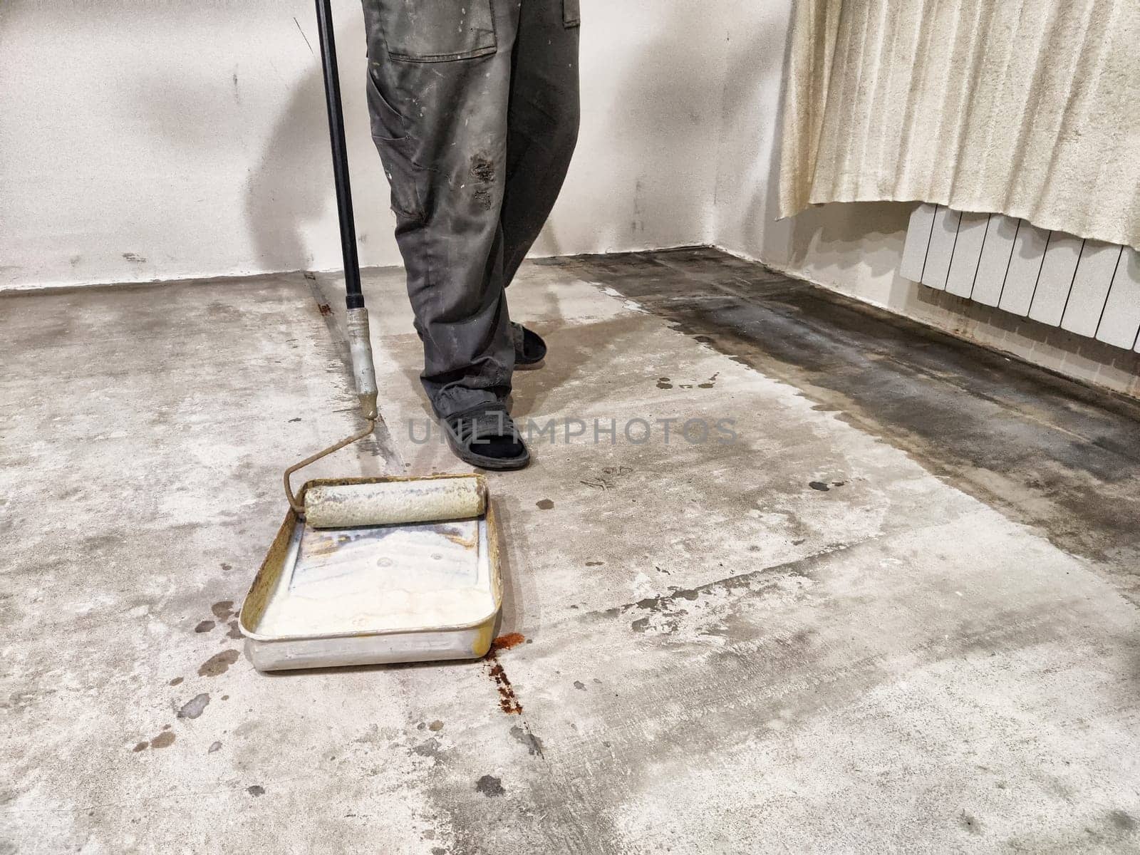 Repair work involves priming the floor in preparation for tile installation in a residential setting, ensuring a strong foundation.