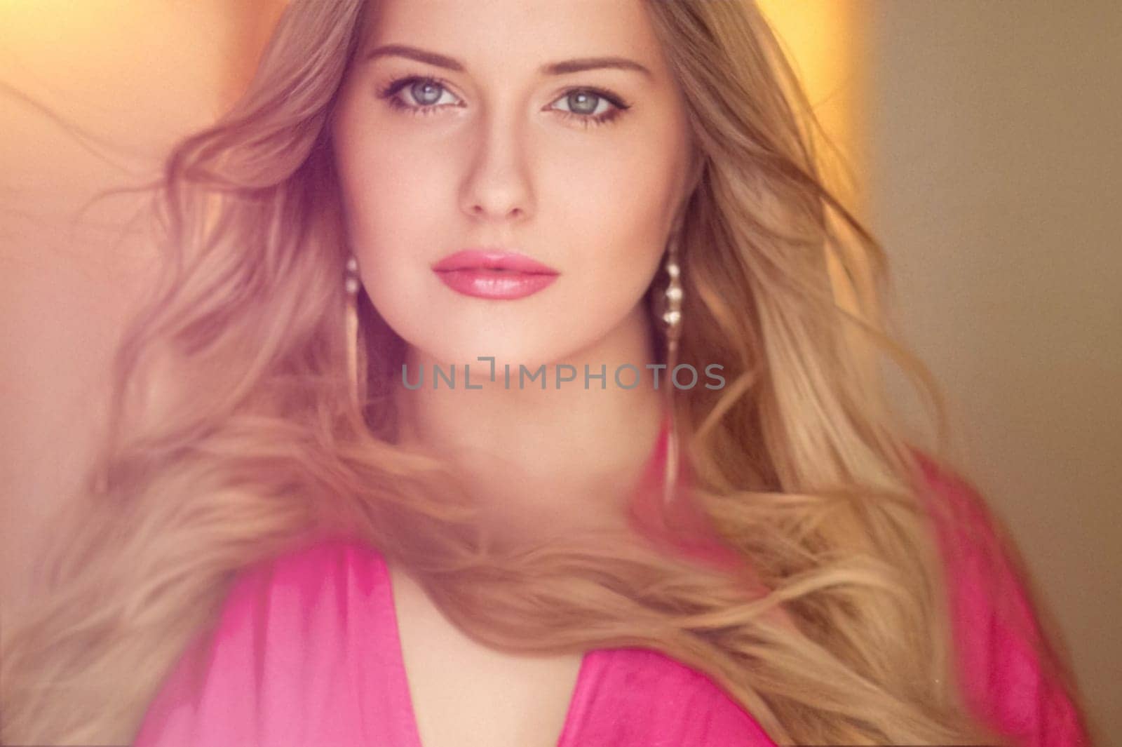 Woman with blue eyes and long, voluminous blonde hair styled in soft curls, wearing pink dress and elegant earrings, dreamy and feminine look idea