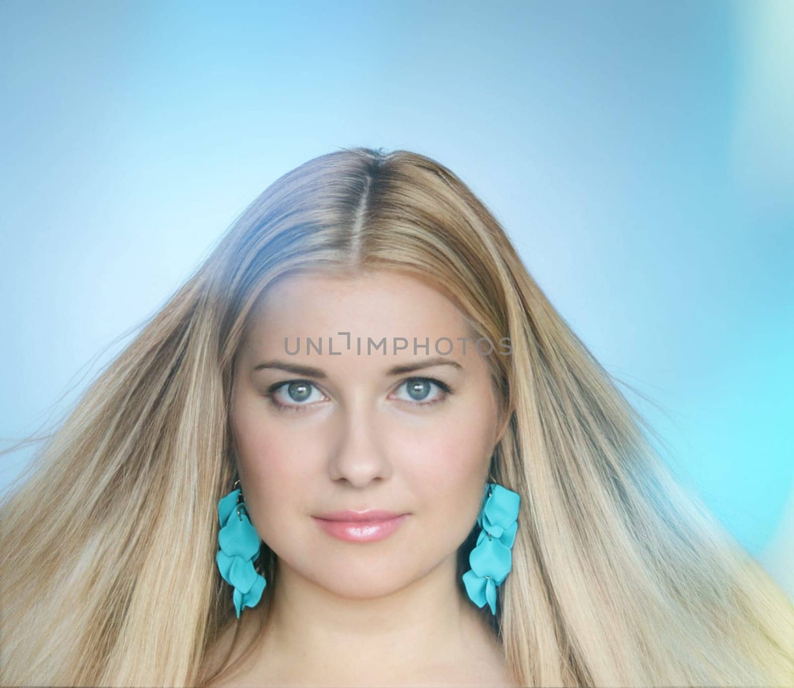Woman with radiant blonde hair flowing gracefully, adorned with turquoise statement earrings. A serene blue background highlights her elegance and poised beauty, evoking a fresh and vibrant charm look