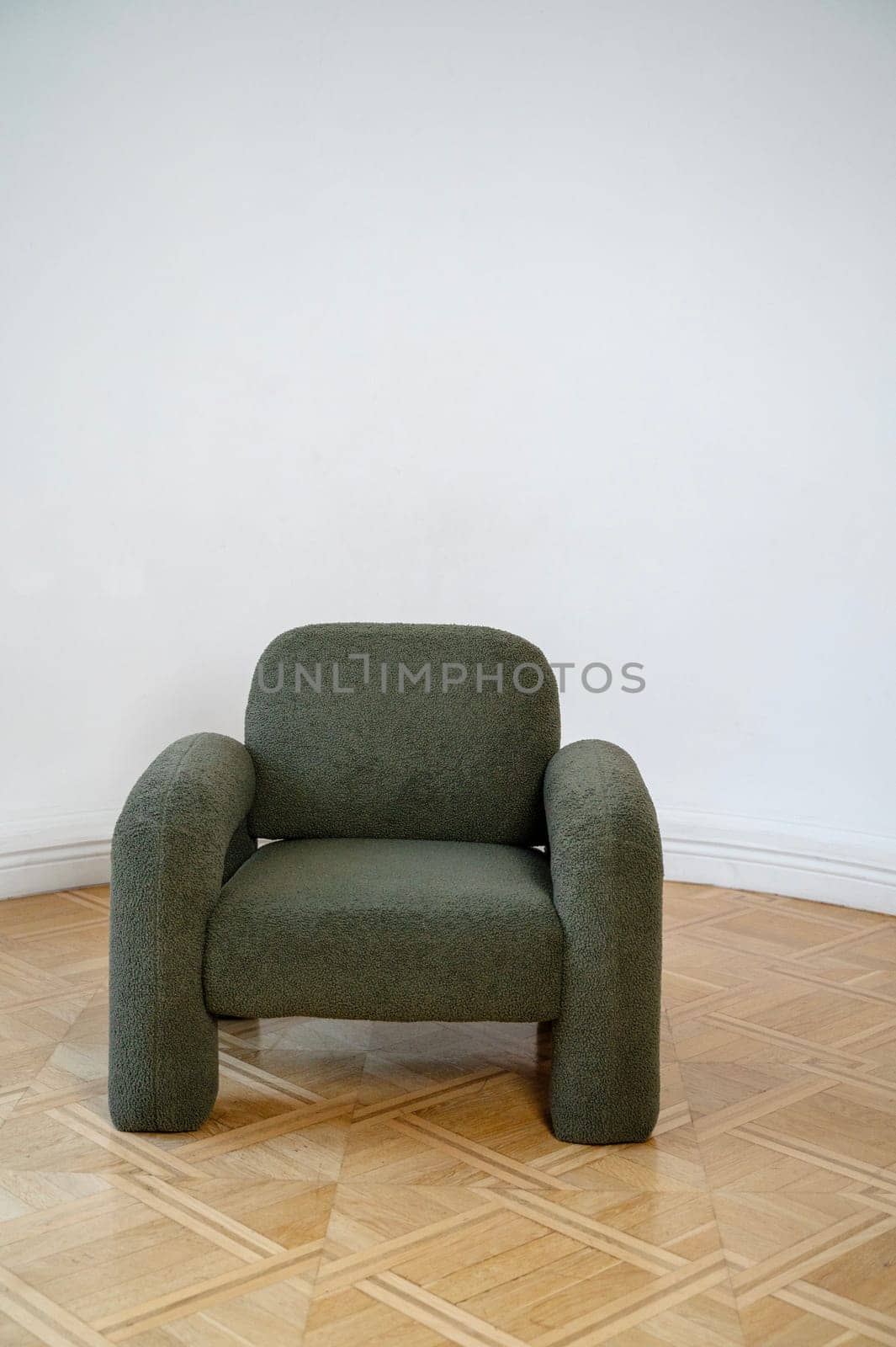 A chair sitting in a room. High quality photo,A dark gray minimalist armchair stands in the room. A beautiful wooden floor. There is warm-colored parquet on the floor.