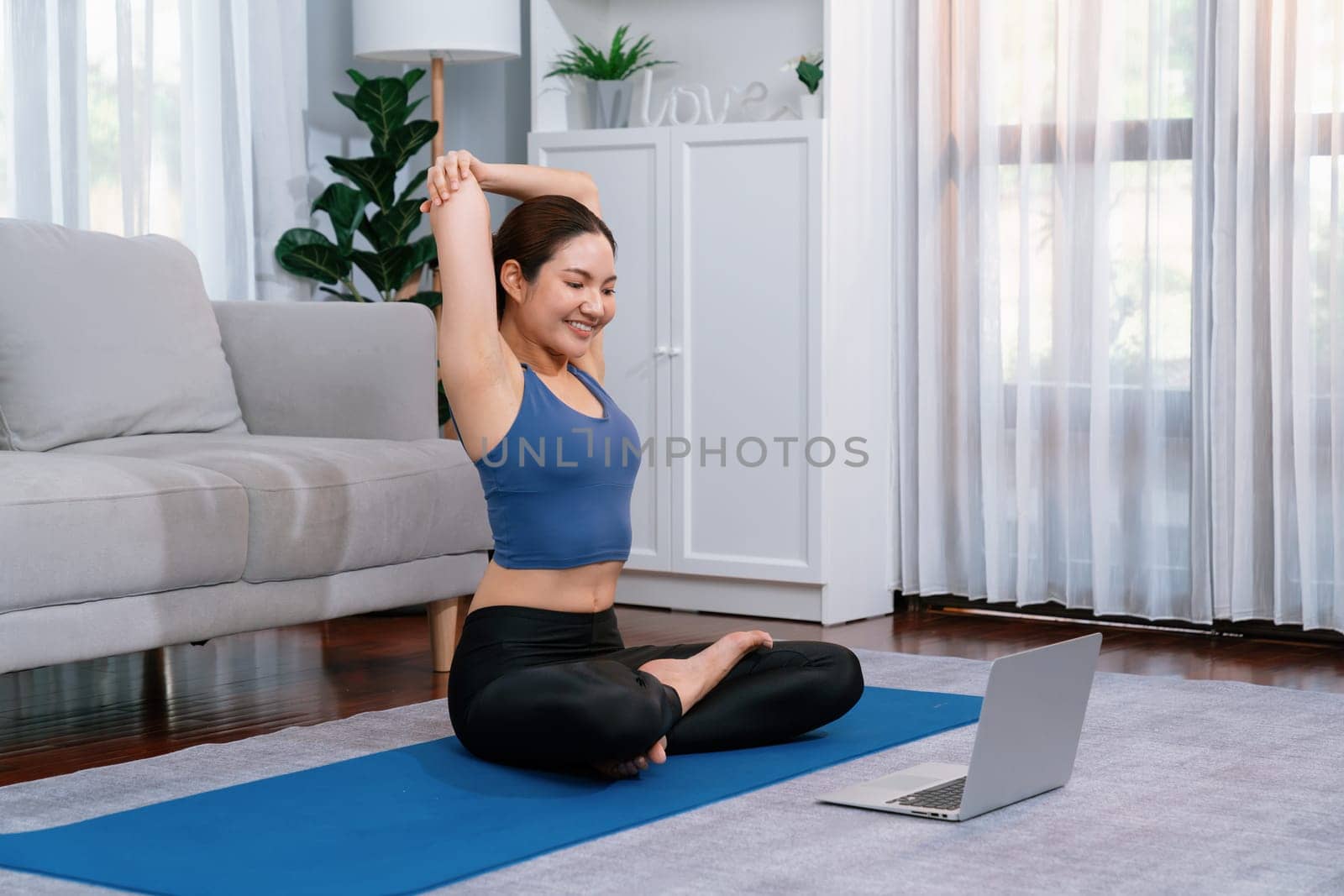 Asian woman in sportswear and yoga exercise on fitness mat with laptop. Vigorous by biancoblue