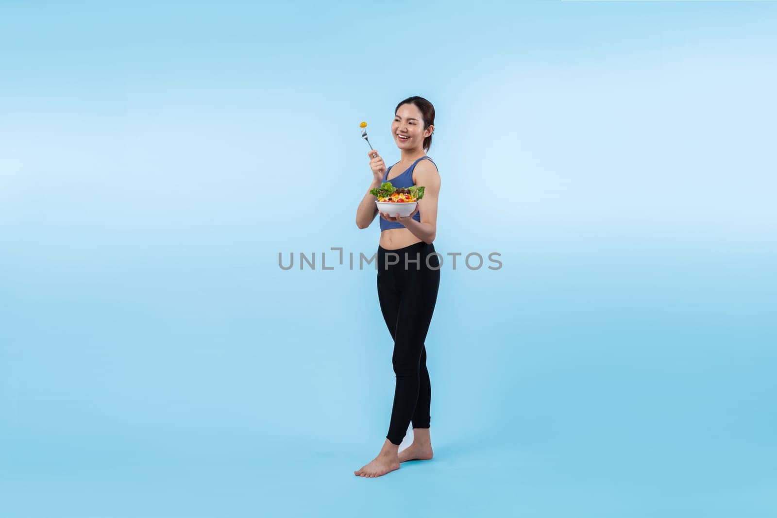 Asian woman in sportswear holding salad bowl on isolated background. Vigorous by biancoblue