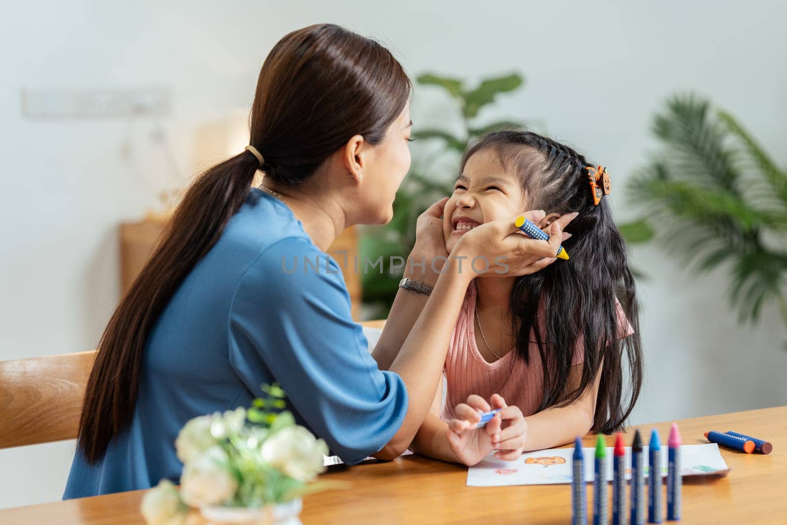 Happy family. Mother and daughter drawing together. Adult woman helping to child girl.