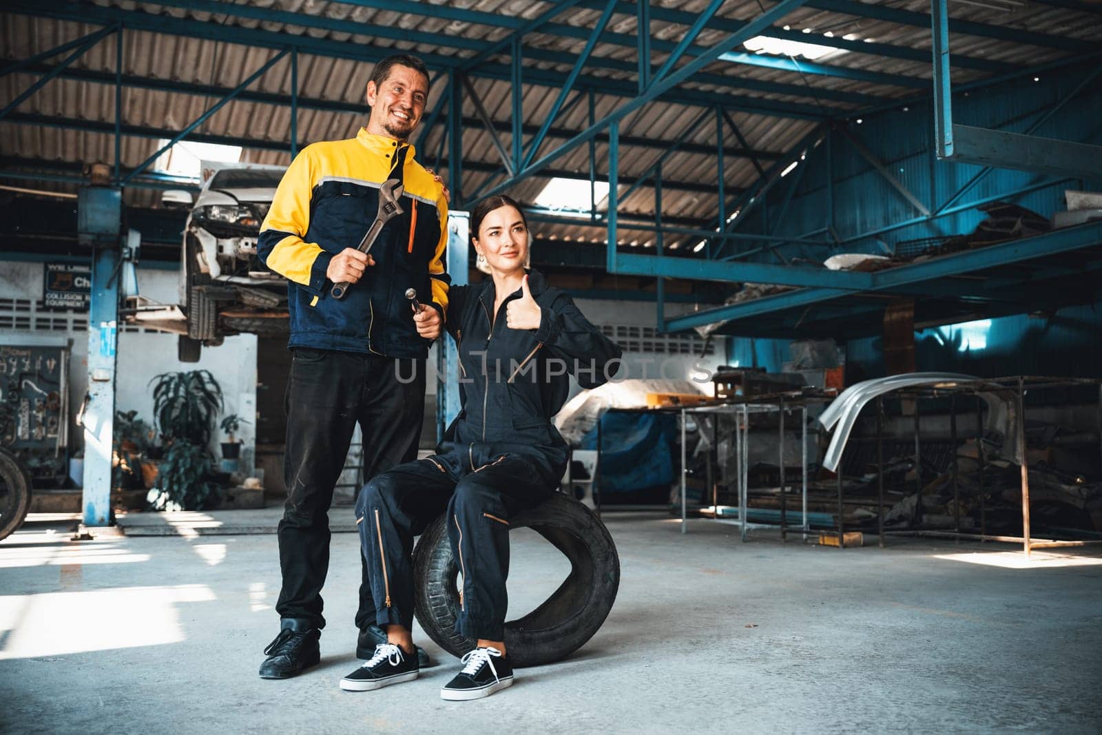 Two happy vehicle mechanic celebrate and high five after made successful car inspection or repair in automotive service car workshop. Technician team enjoy accomplishment together in garage. Oxus