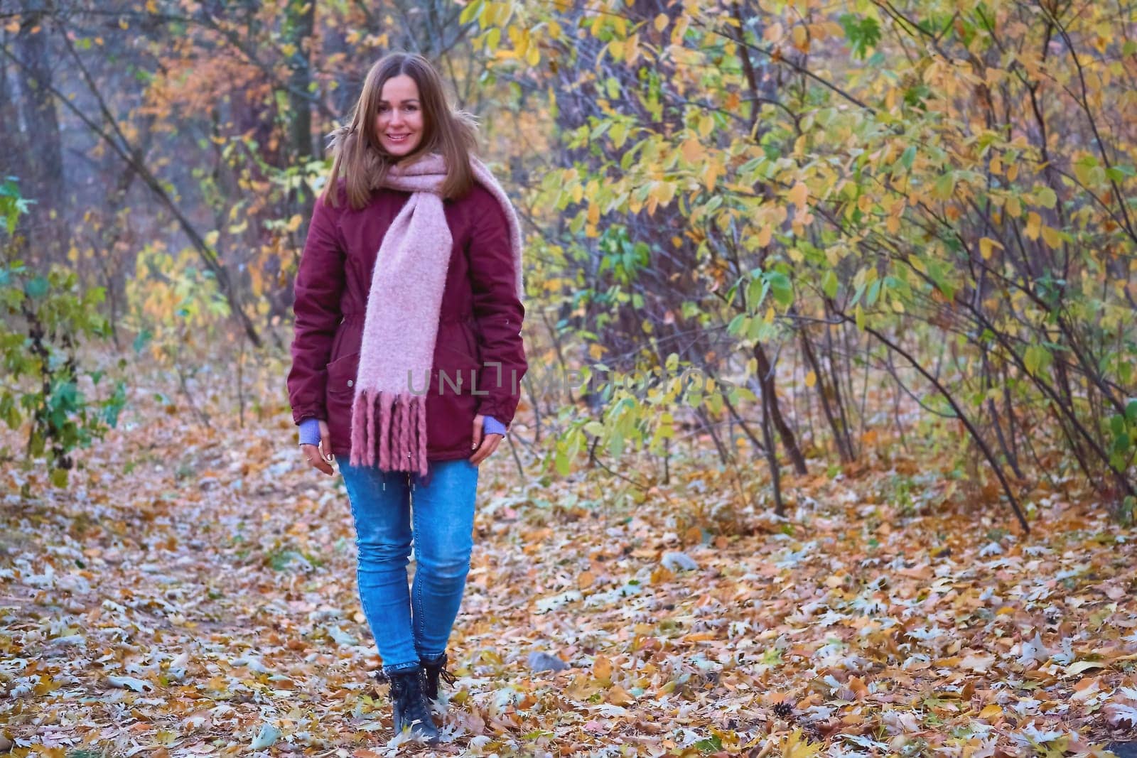 Young attractive woman in a red jacket and jeans in the autumn forest by jovani68