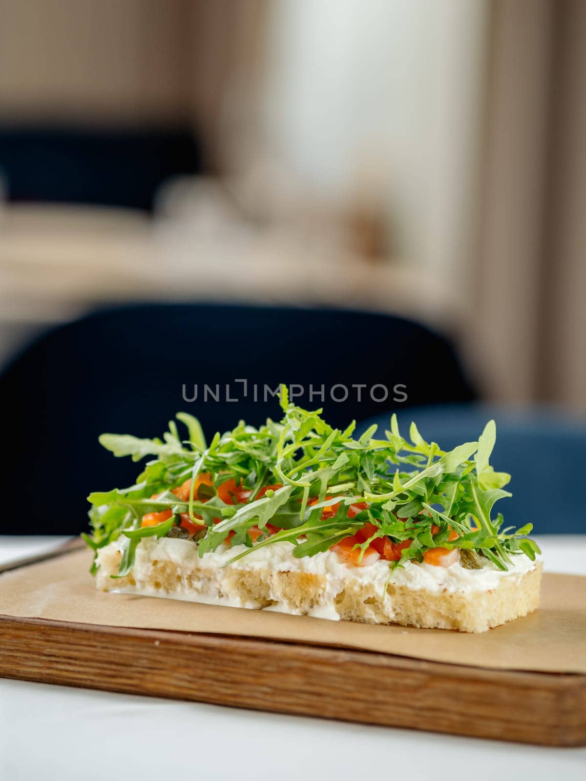 Tasty bruschetta with salmon and arugula on restaurant table in interior