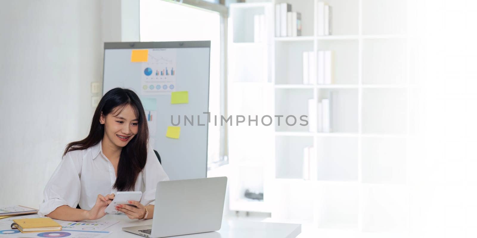 Businesswoman using a calculator to calculate numbers on a company's financial documents, she is analyzing historical financial data to plan how to grow the company. Financial concept.