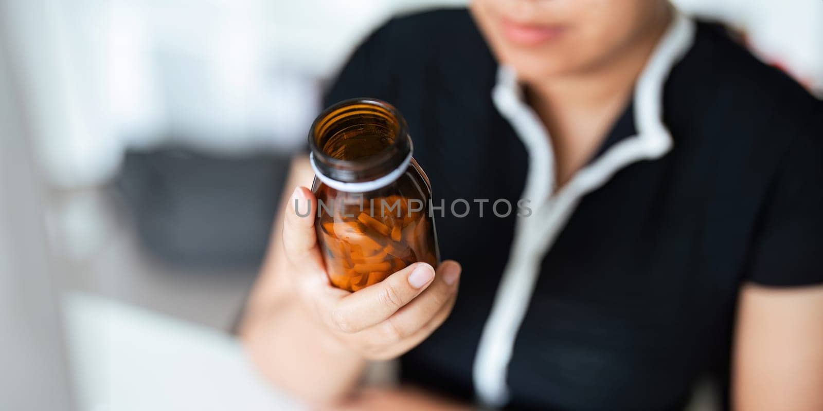 Woman hold bottle of drug tablet painkiller or vitamin supplement reading label ready to organizing medicine at home. medication healthcare concept.
