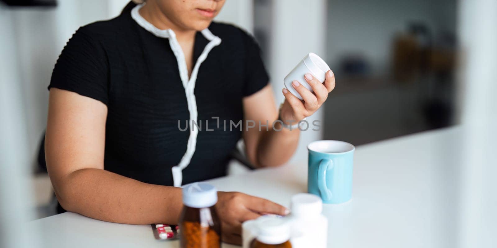 Woman hold bottle of drug tablet painkiller or vitamin supplement reading label ready to organizing medicine at home. medication healthcare concept.