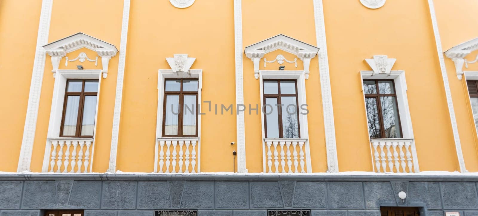 Elegant classical windows decorated with stucco ornaments on beige antique facades. Vintage classic architecture. Banner by Satura86