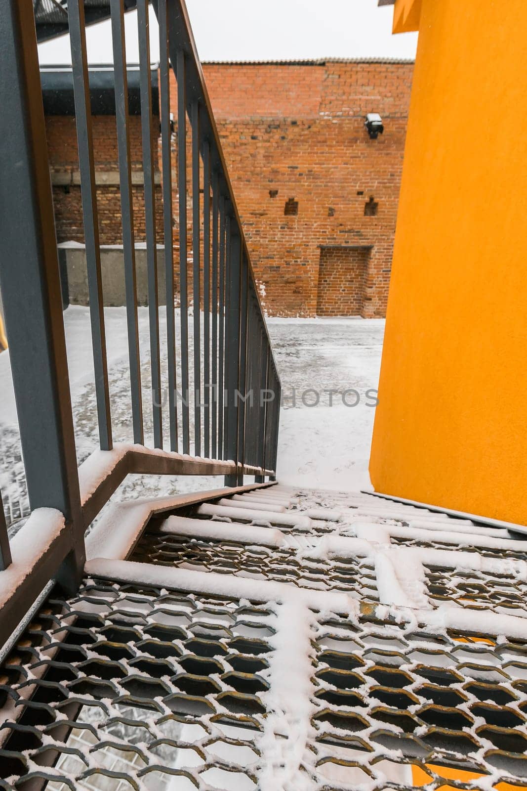 Fire exit stair of large factory building in winter season with snow. Galvanised metal stair step. by Satura86