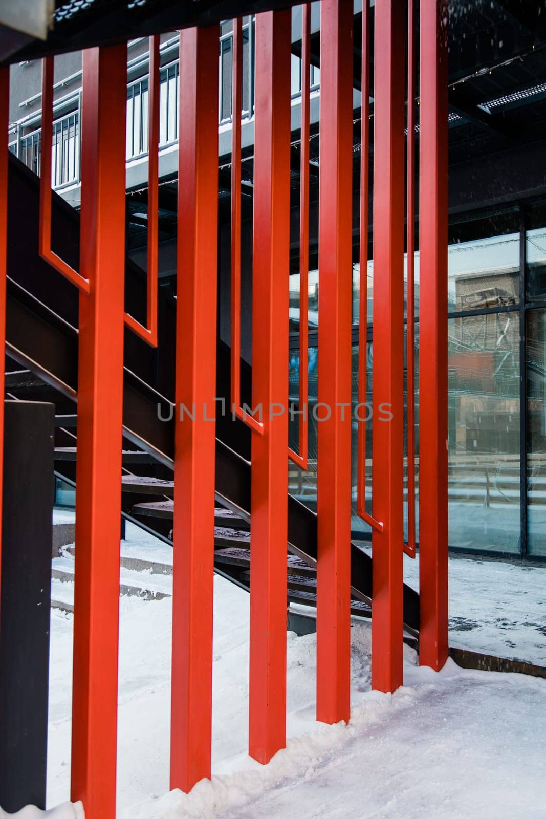 Fire escape ladder or emergency exit with steel staircase on wall of modern industrial building with red metal constructions by Satura86