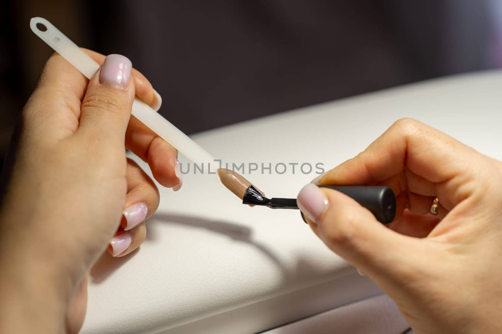 A manicurist applies gel nail polish to empty tips as a sample by AnatoliiFoto