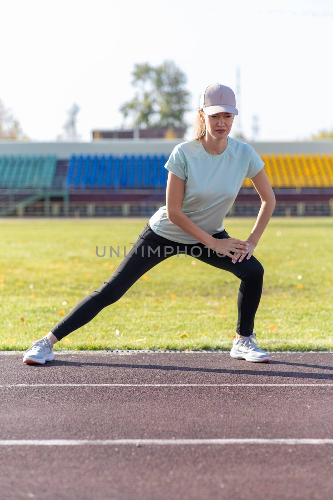 A young beautiful woman in sportswear plays sports at a local stadium by AnatoliiFoto