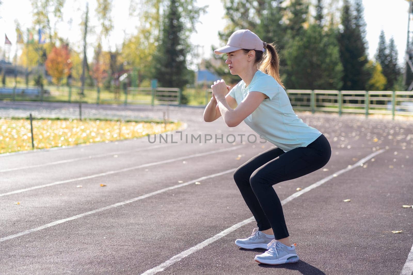 A young beautiful woman in sportswear plays sports at a local stadium by AnatoliiFoto