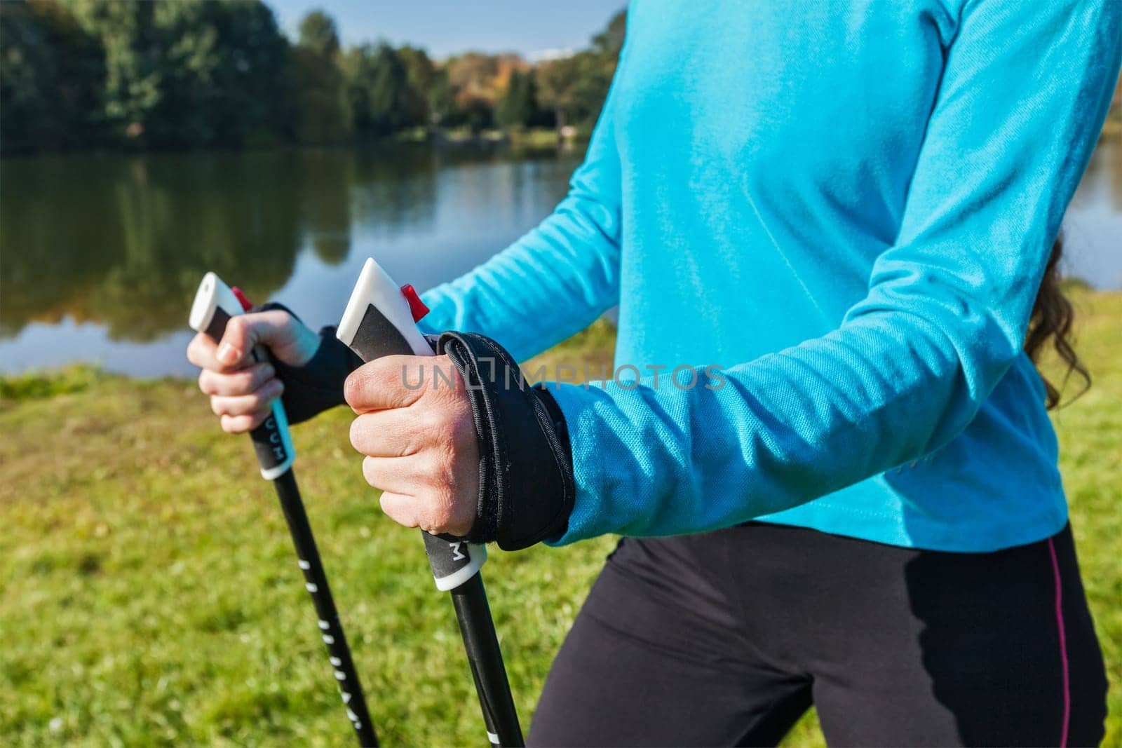 Nordic walking exercise adventure hiking concept - closeup of woman's hand holding nordic walking poles
