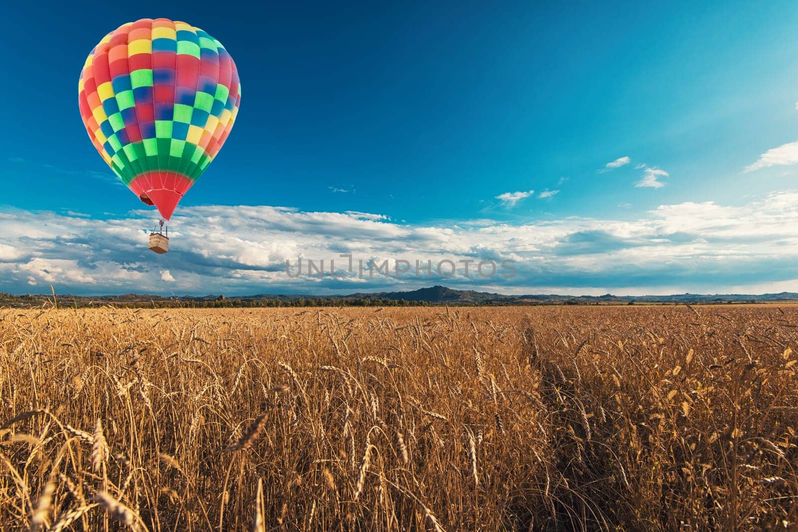 Balloon above the wheat field in mountains on sunset