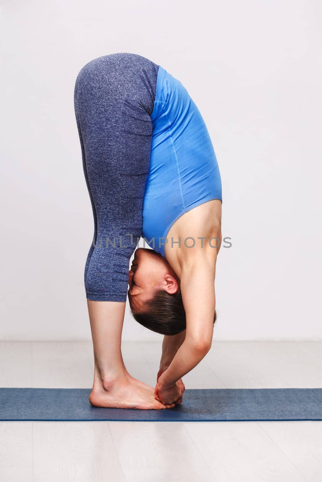 Woman doing Ashtanga Vinyasa yoga asana Padangusthasana - foot t by dimol