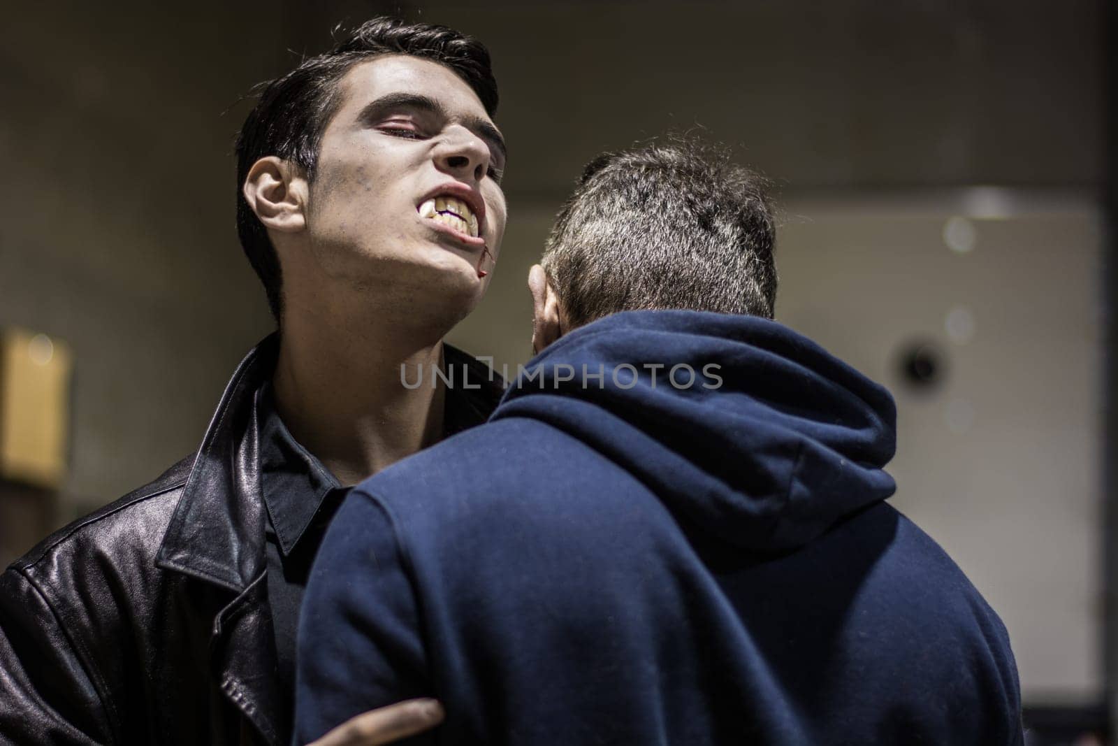 A young, scary male vampire about to bite another man on the neck. Halloween theme
