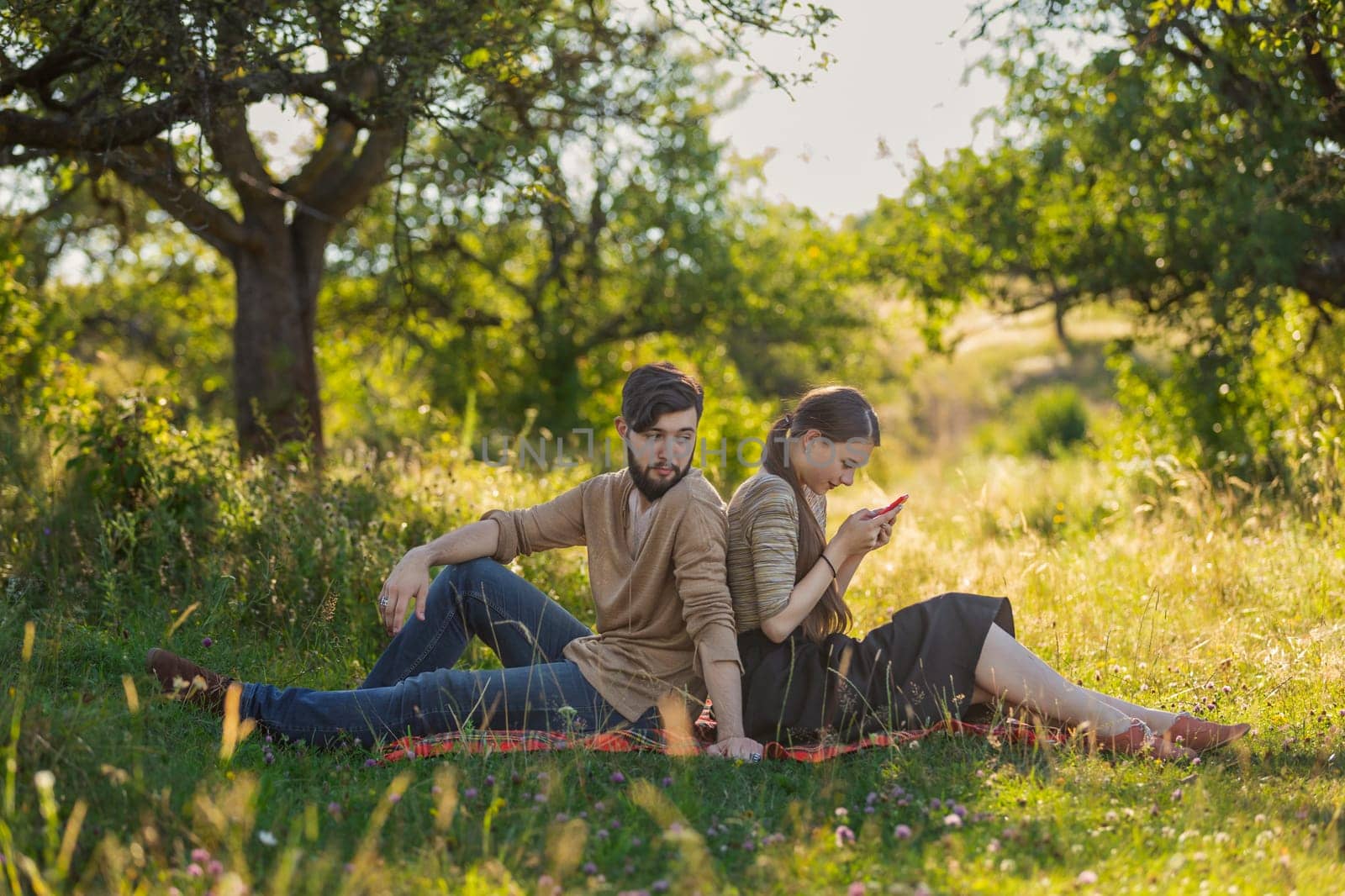 Young couple in nature, a girl with a phone is texting someone