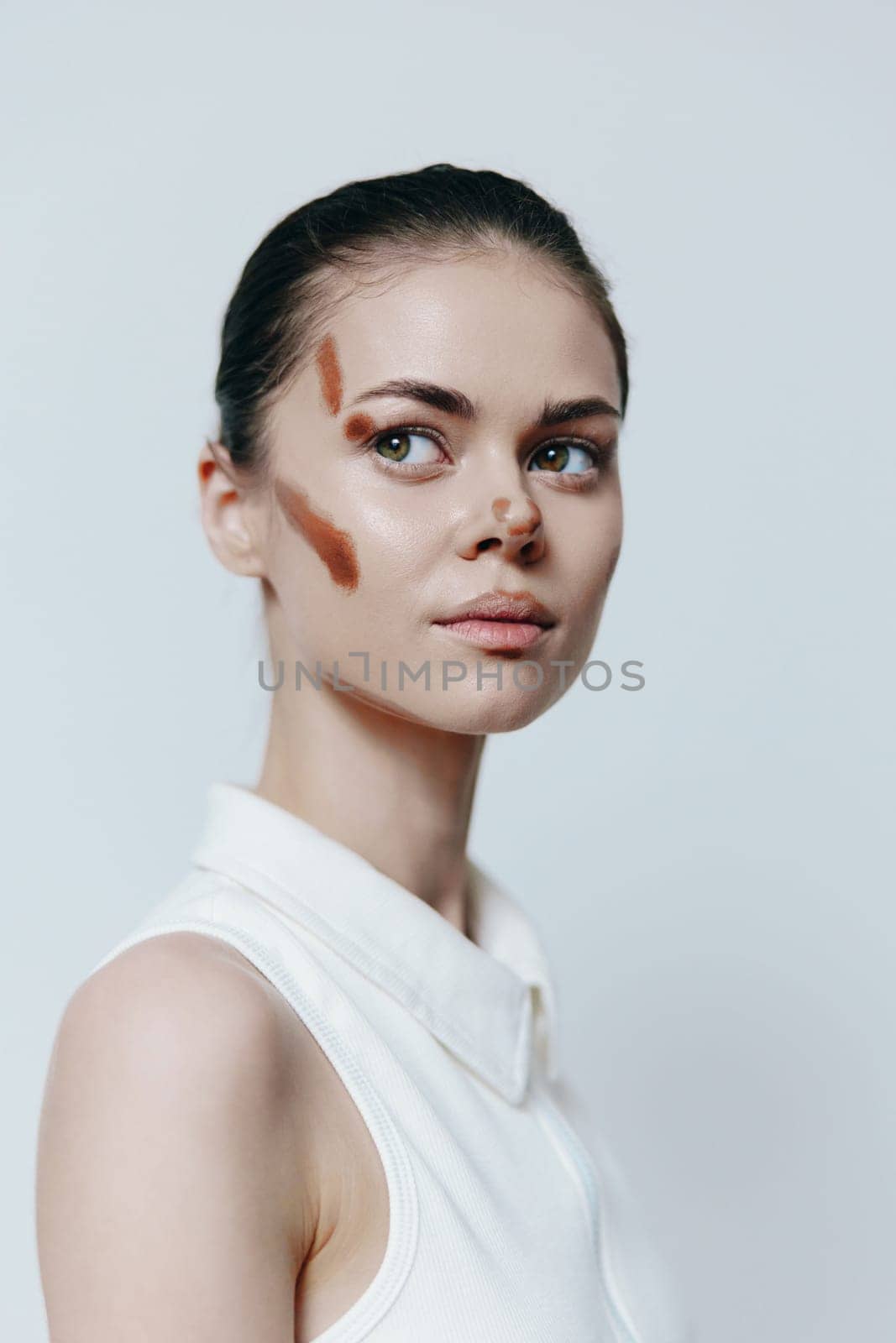 This artistic portrait features a young model with unique makeup, highlighting her beauty and creativity. The minimalist background enhances the focus on her expression and style.