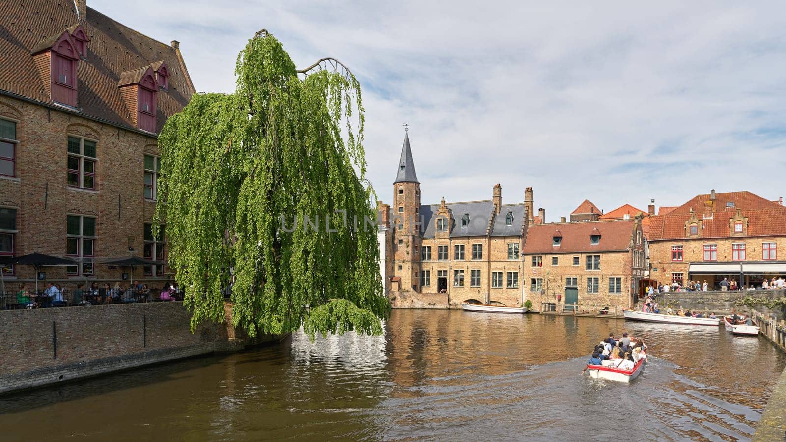 Bruges, Belgium – May 13, 2024: Canal at Rozenhoedkaai, in the old town of Bruges in Belgium with excursion boats for tourists