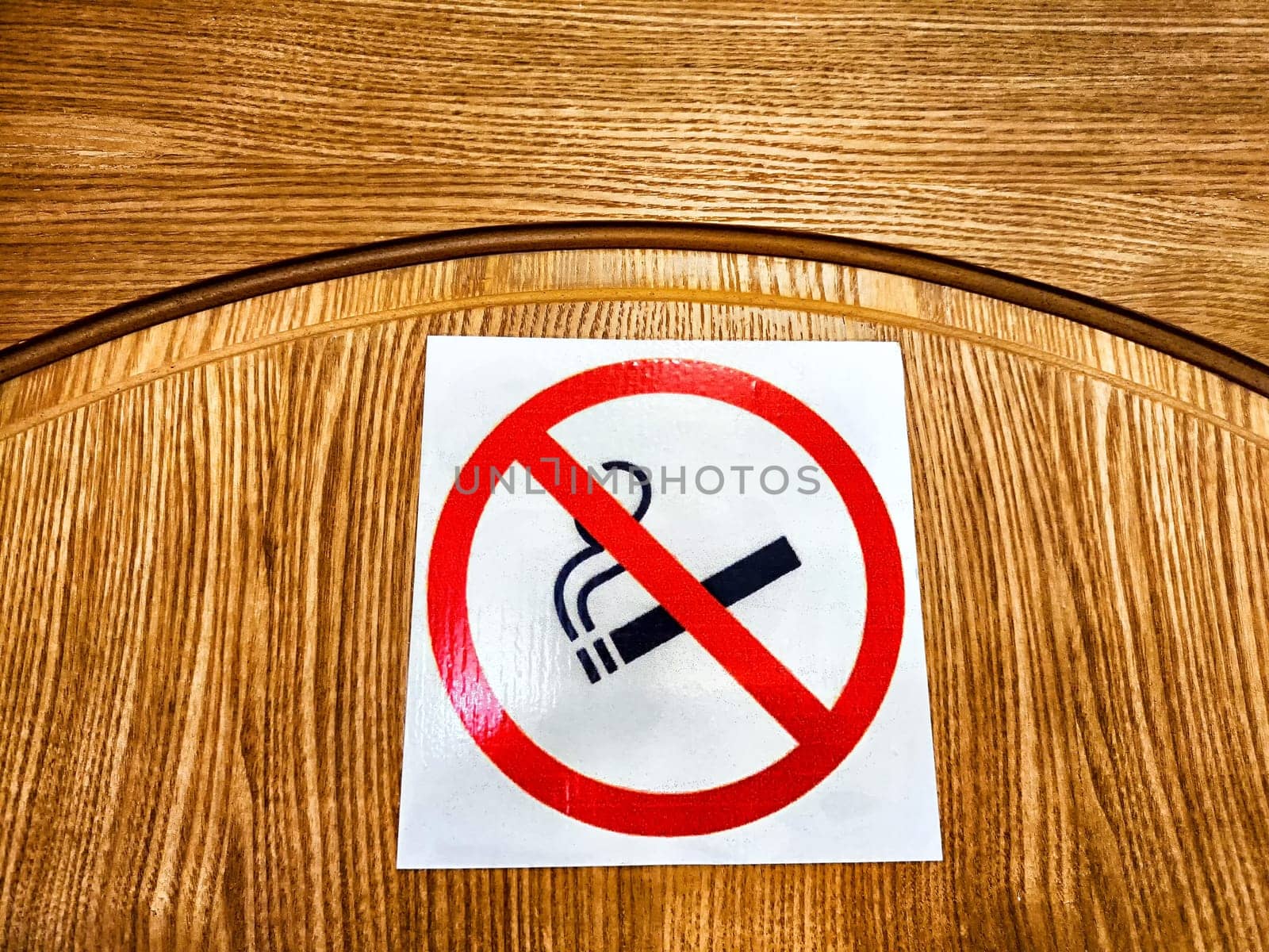 A no smoking sign is placed on a wooden table, indicating a smoke-free zone while indoors.