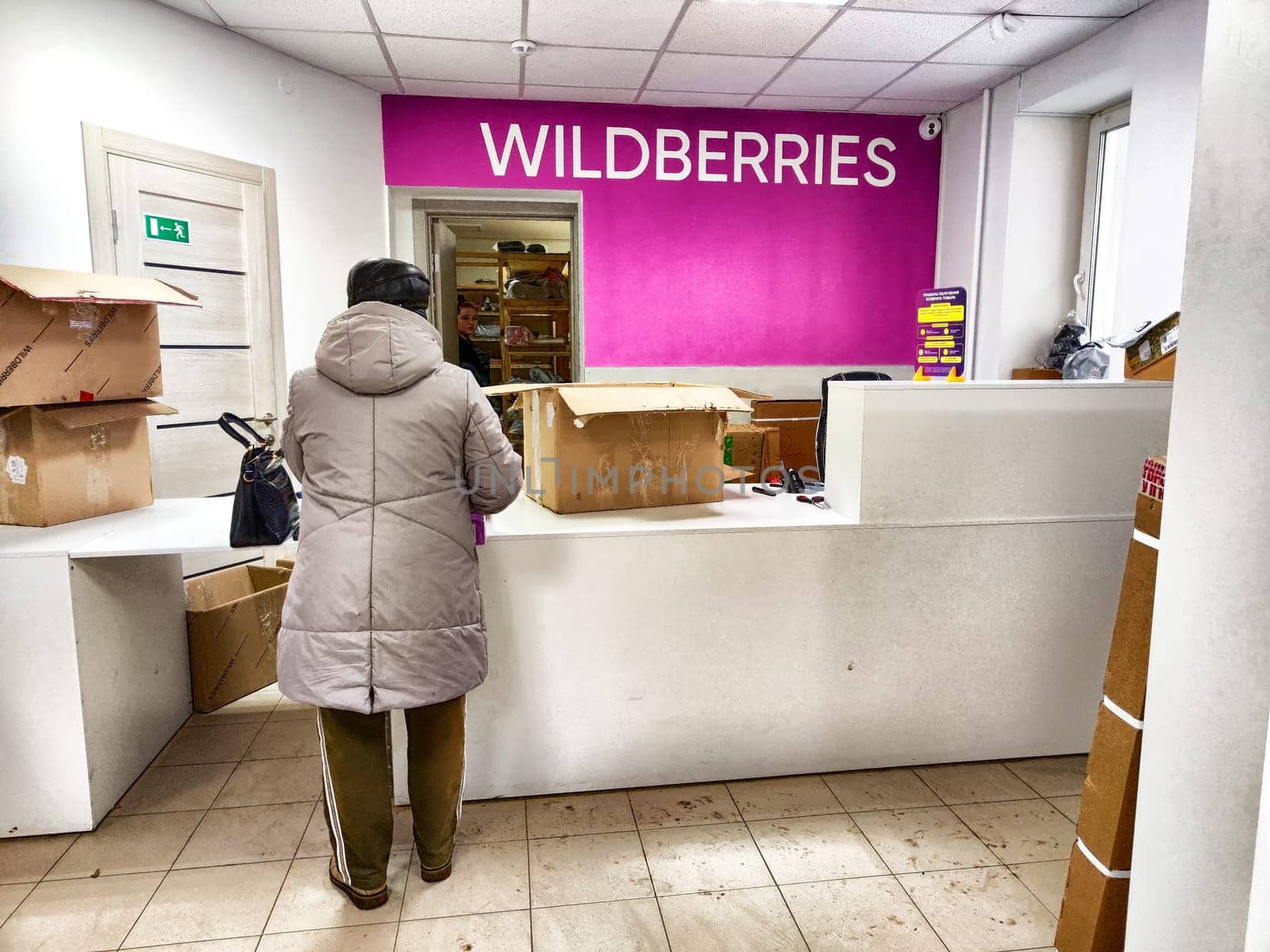 Kirov, Russia - November 16, 2024: A customer stands at a service counter in the vibrant Wildberries marketplace, surrounded by packing boxes.