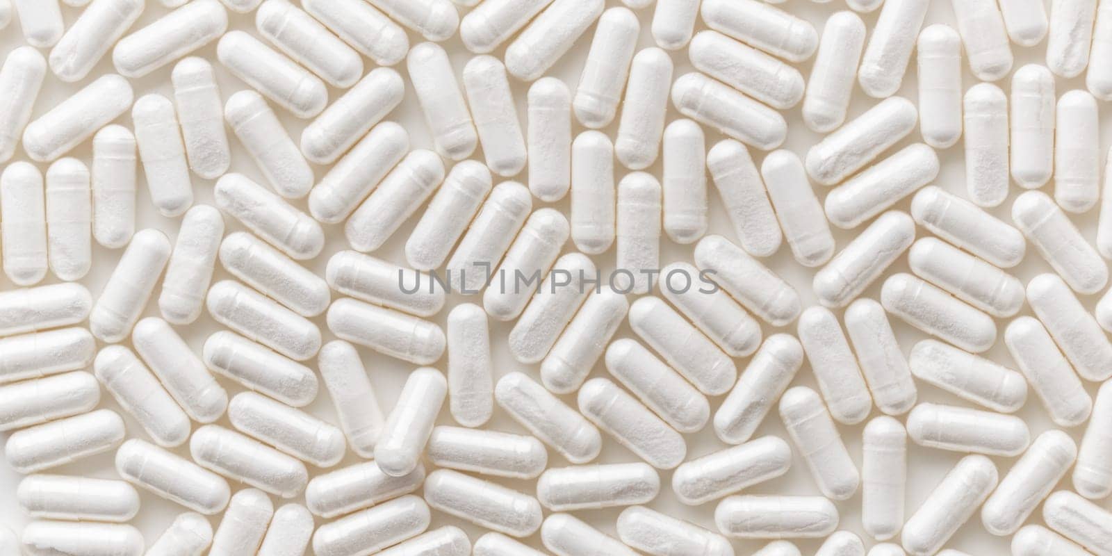 Scattered white medicine, pills or capsules on white table. Mock up background from top view. Medical, pharmacy and healthcare. High-quality photo mock-up banner. Healthy Bio Supplements. Pharmacology