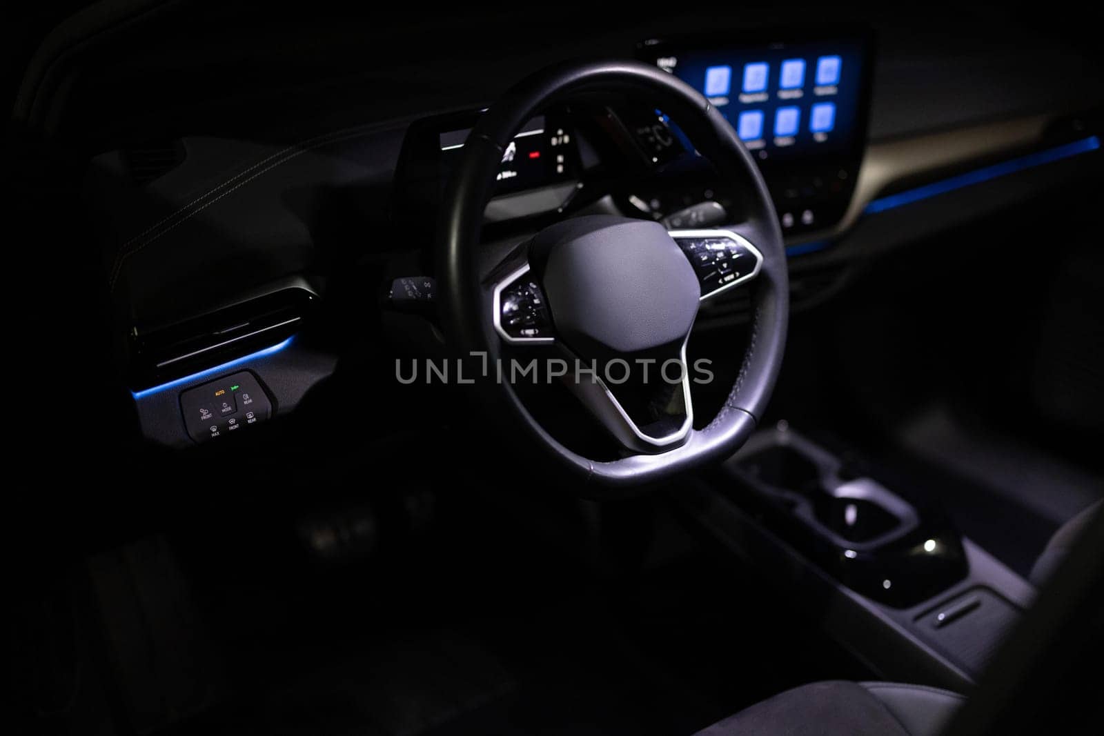 Black leather cockpit with blue ambient light. Electric car Interior view in the cabin. Expensive electric car interior with steering wheel. Interior of prestige modern electric car.