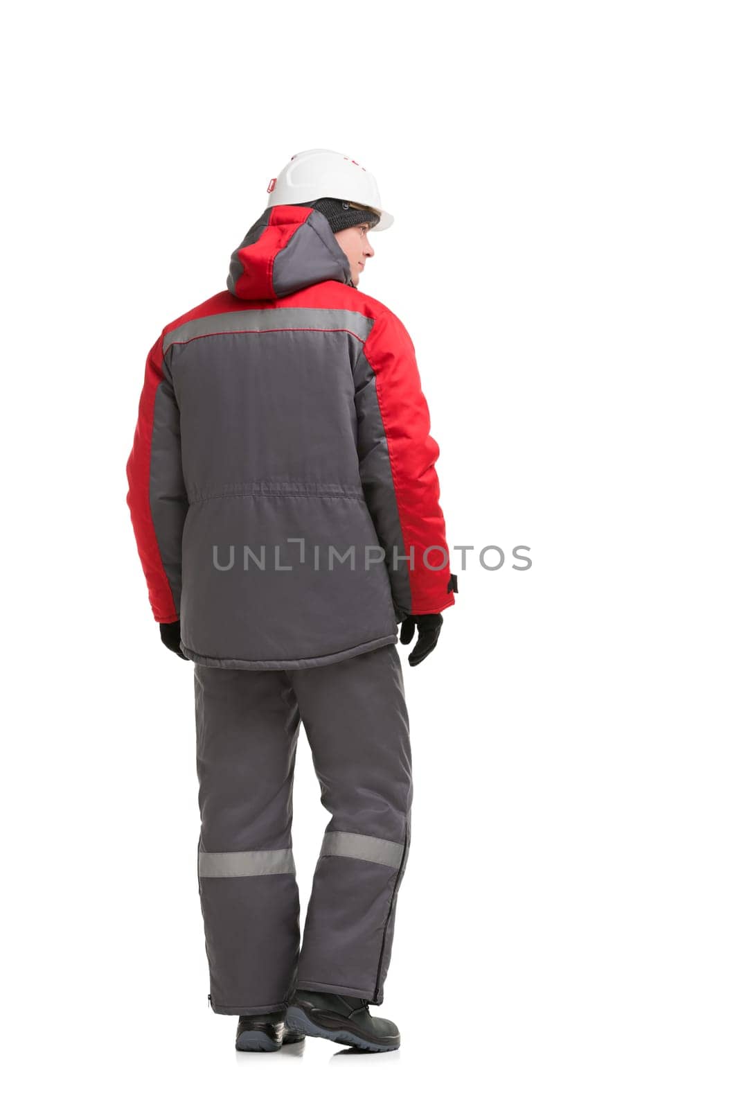 Male in gray and red work clothes and white protective helmet isolated full-length rearview
