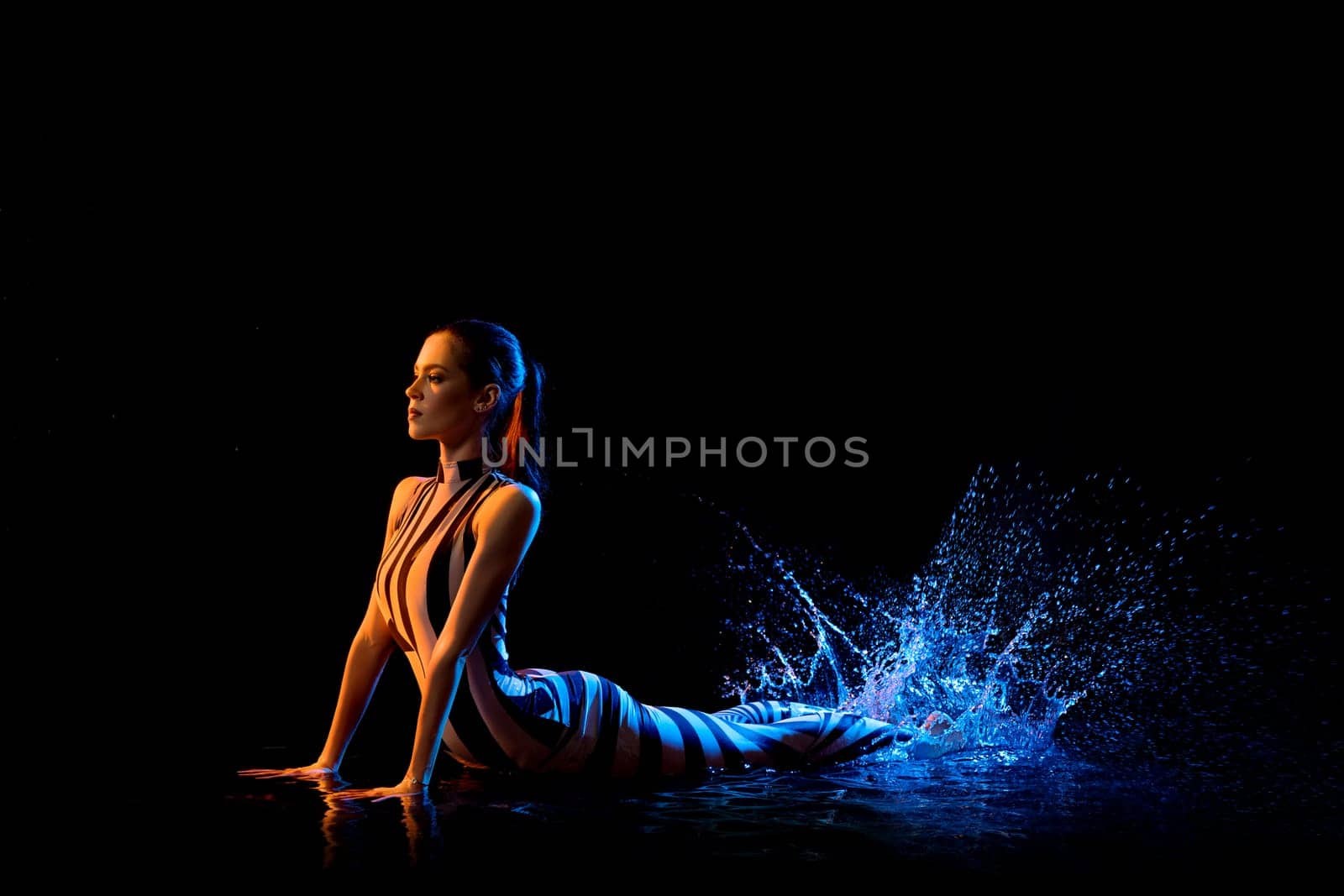 Fitness model lying on the floor shot in water drops in the dark room