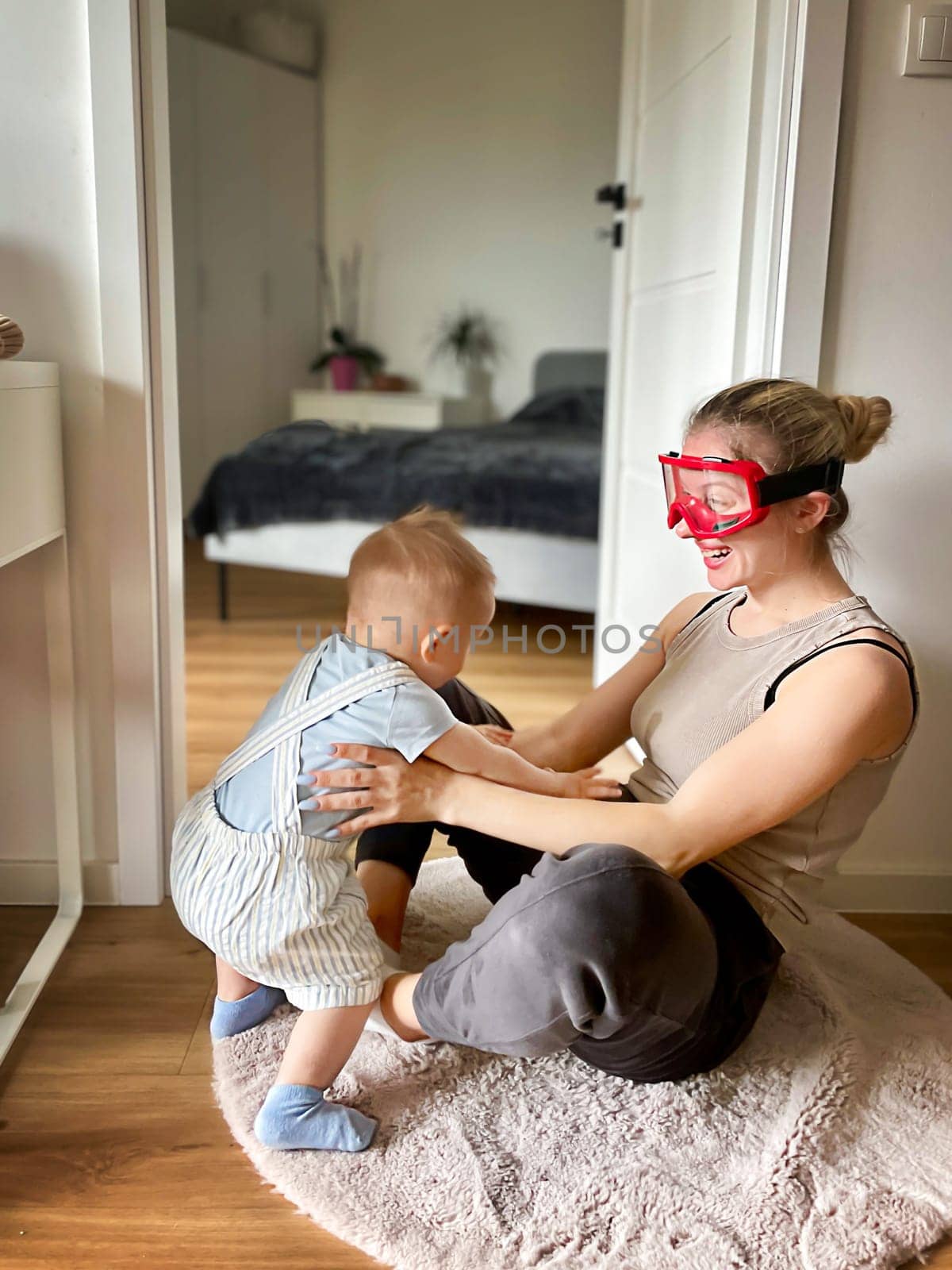 Young woman wearing big glasses having fun playing with her son. High quality photo
