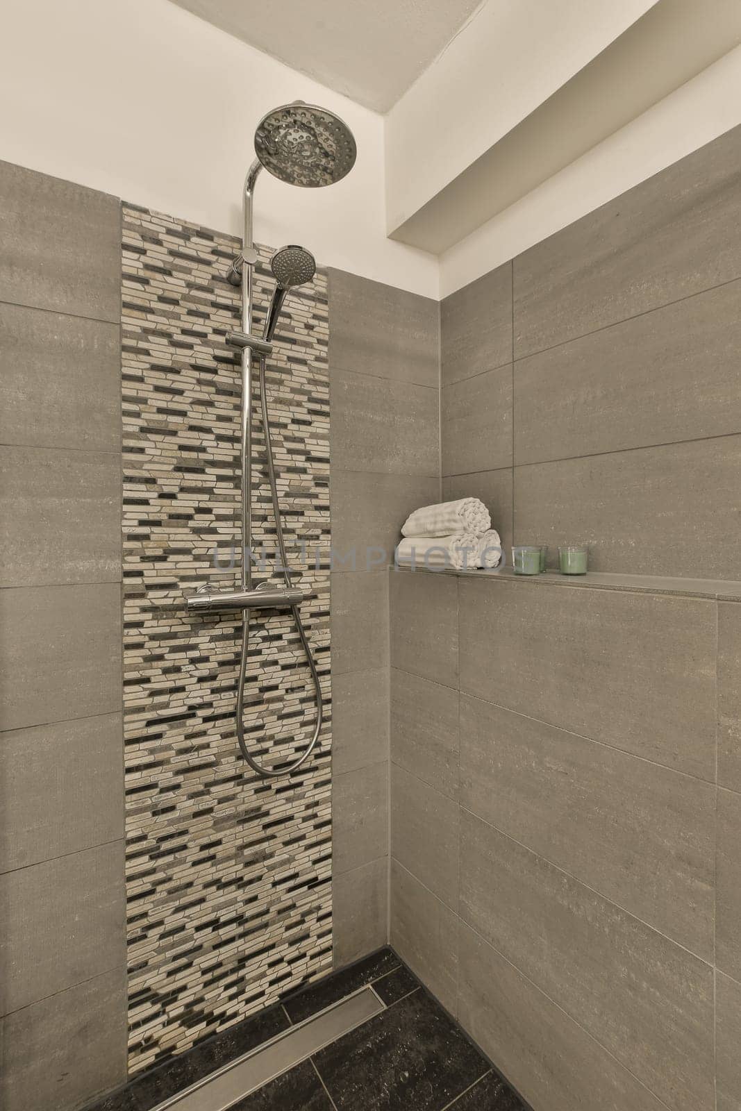 a shower in a bathroom with gray tiles and a by casamedia