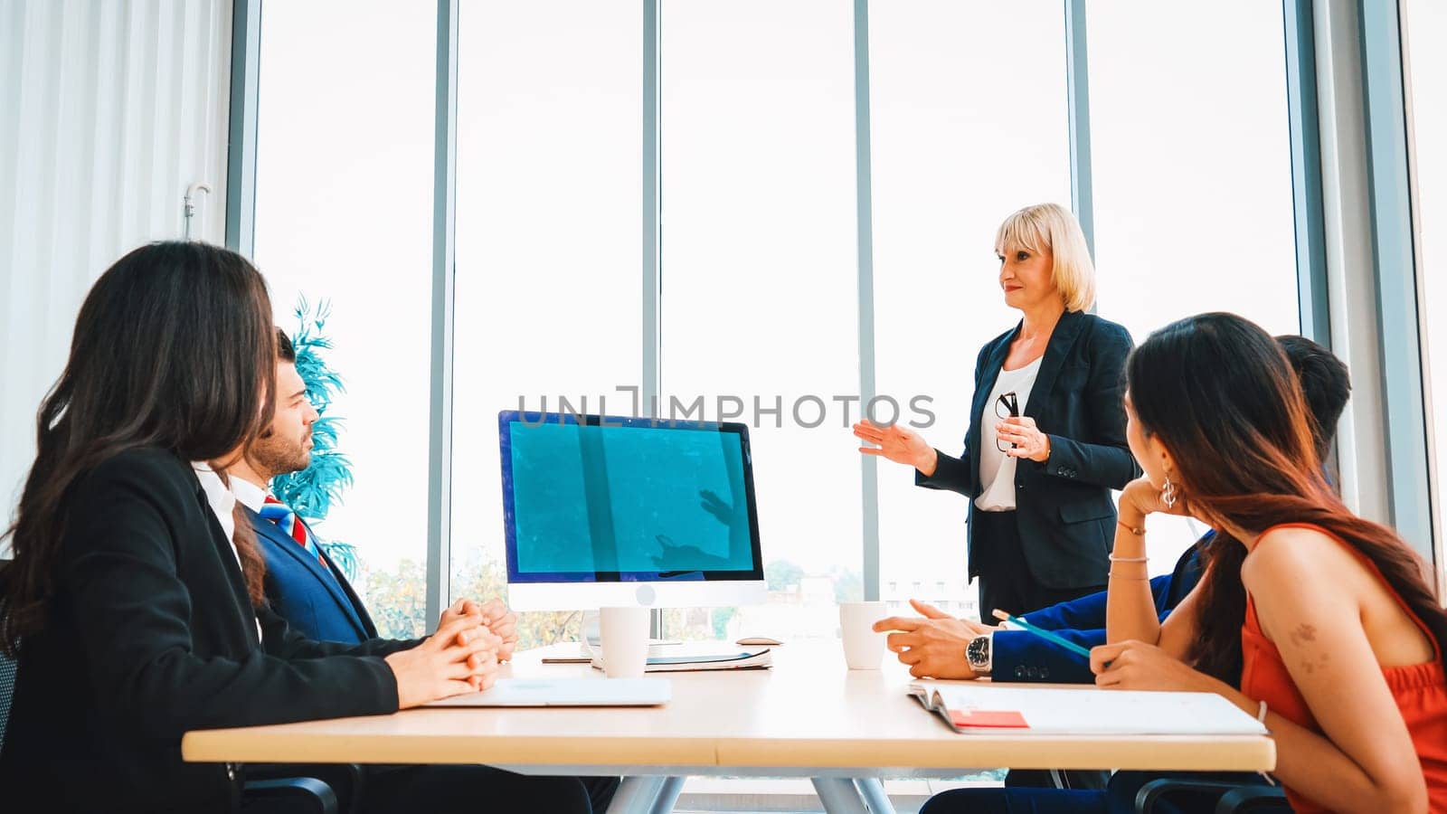 Business people in the conference room with green screen chroma key TV or computer on the office table. Diverse group of businessman and businesswoman in meeting on video conference call . Jivy