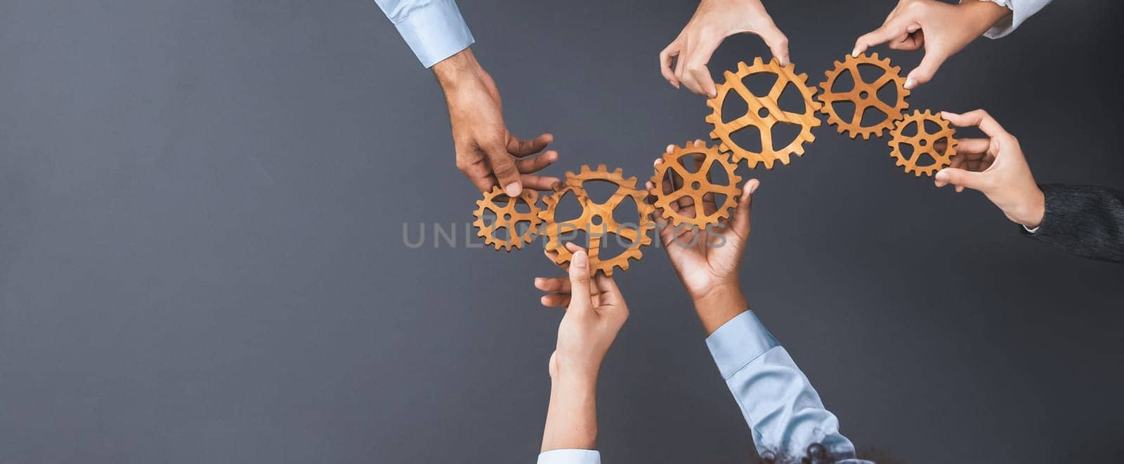 Panoramic shot top view of business people holding cog wheel as unity and teamwork in corporate workplace concept. Office worker colleague with symbol of visionary system for business success. Concord