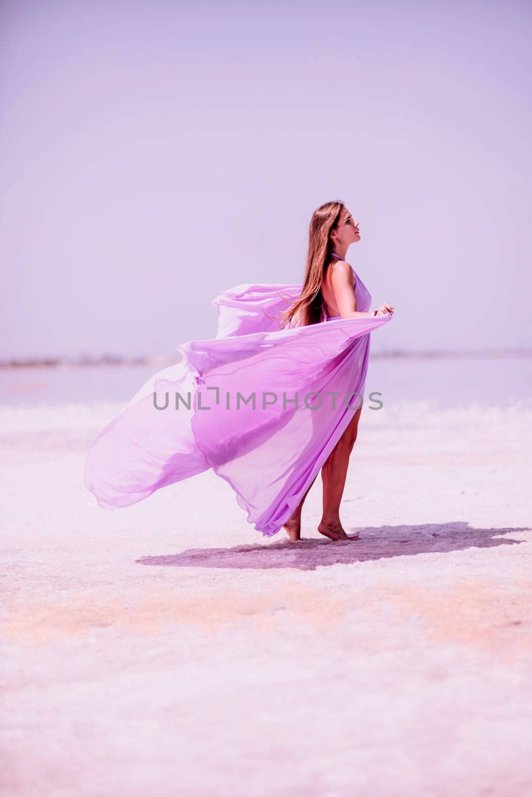 Woman pink salt lake. Against the backdrop of a pink salt lake, a woman in a long pink dress takes a leisurely stroll along the white, salty shore, capturing a wanderlust moment. by Matiunina