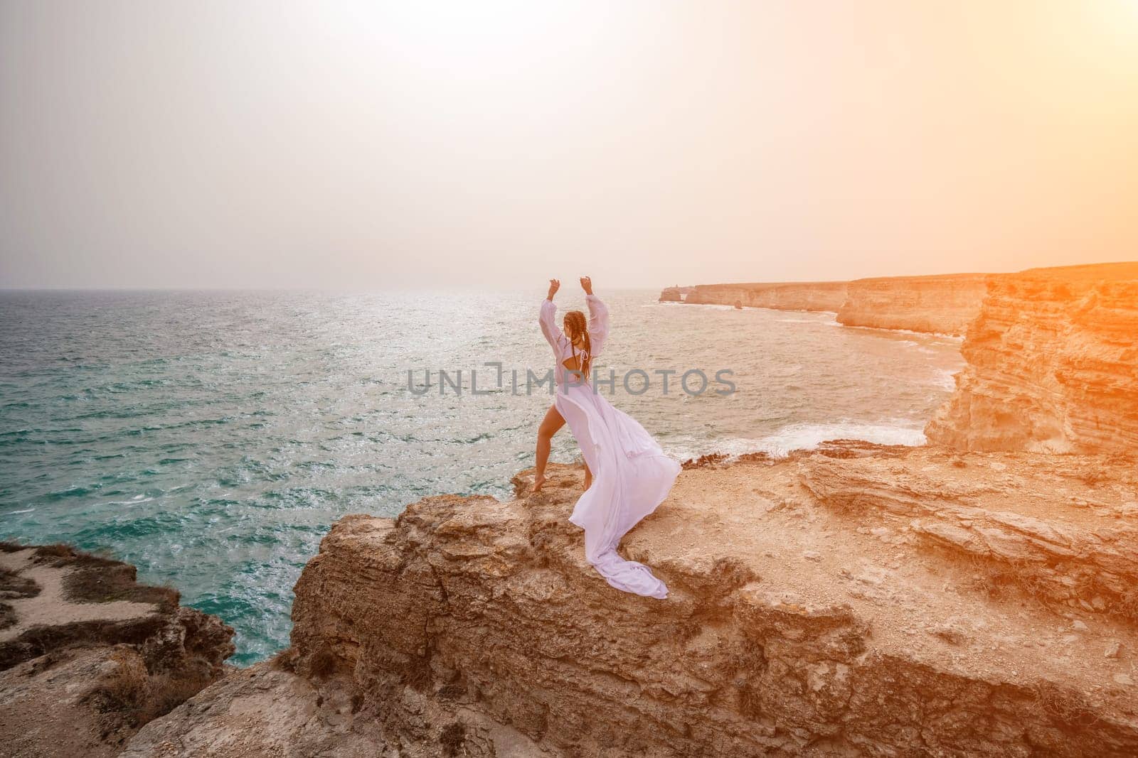 Woman sea white dress. Happy freedom woman on the beach enjoying and posing in white dress. Rear view of a girl in a fluttering white dress in the wind. Holidays, holidays at sea