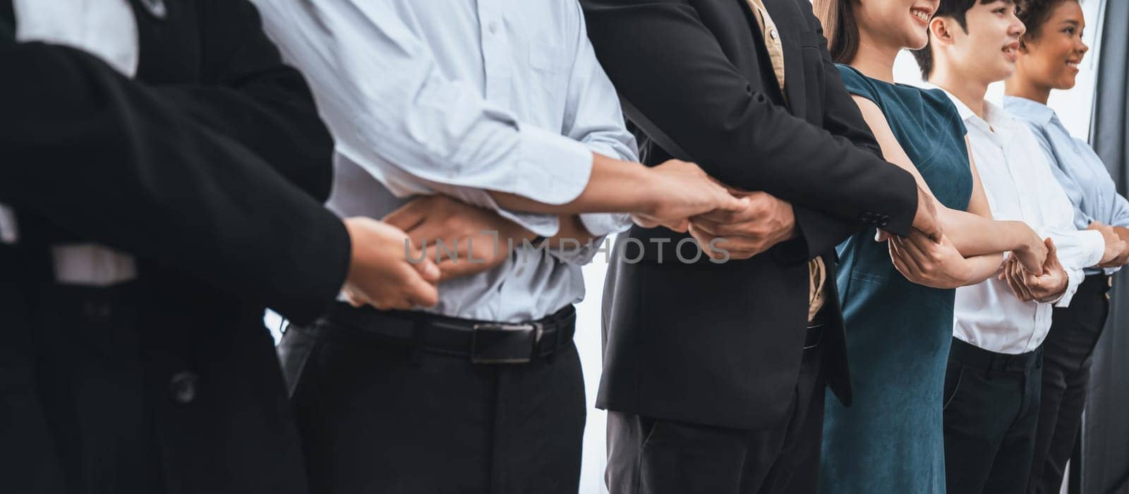 Happy and smiling multiracial office worker hold hand in a line, promoting synergy and collaboration for business success. Diverse professional office worker bond at modern workplace. Concord