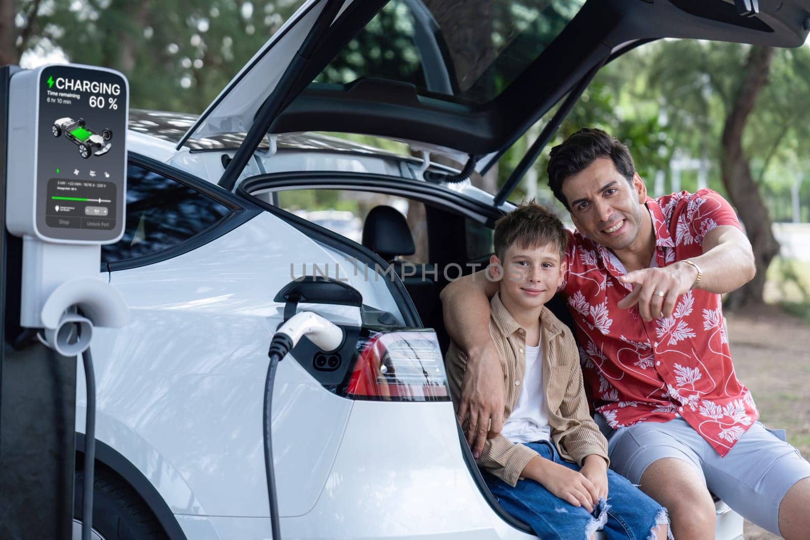 Family road trip vacation with electric vehicle, father and son recharge EV car with green and clean energy. Nature and travel with eco-friendly car for sustainable environment. Perpetual