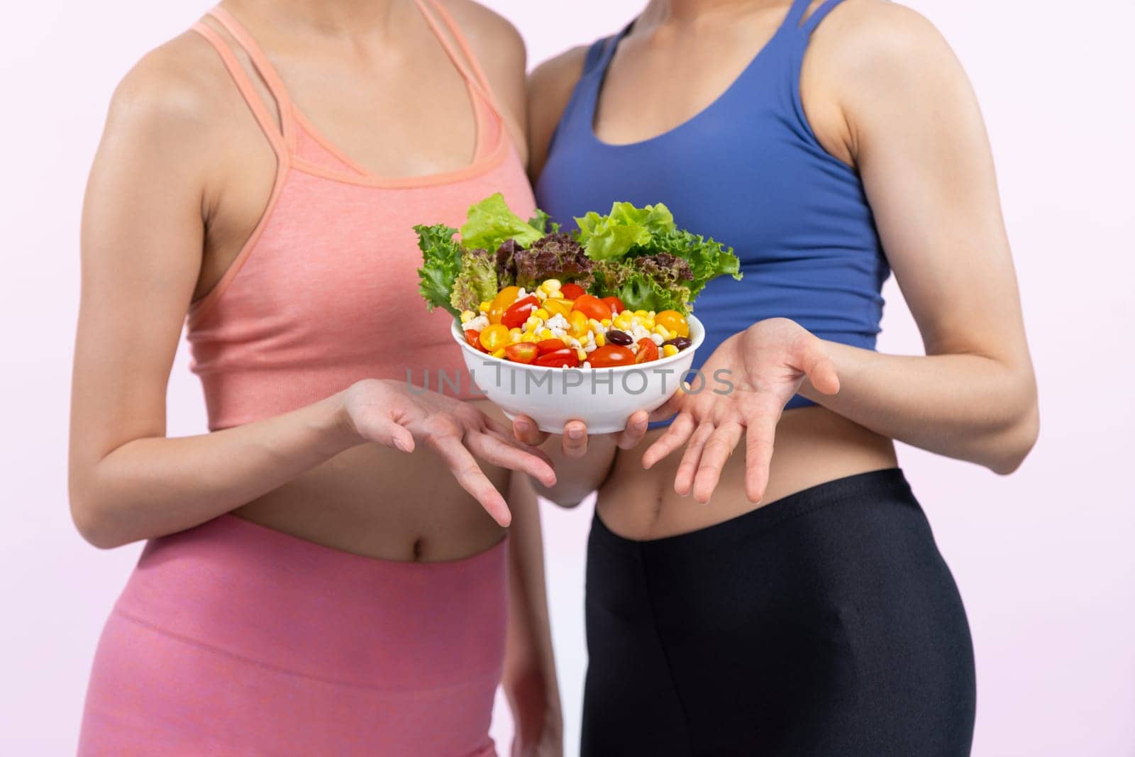 Asian woman in sportswear holding salad bowl on isolated background. Vigorous by biancoblue